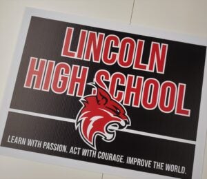 Yard sign with Lincoln High School, lynx head and learn with passion, act with courage improve the world spelled out